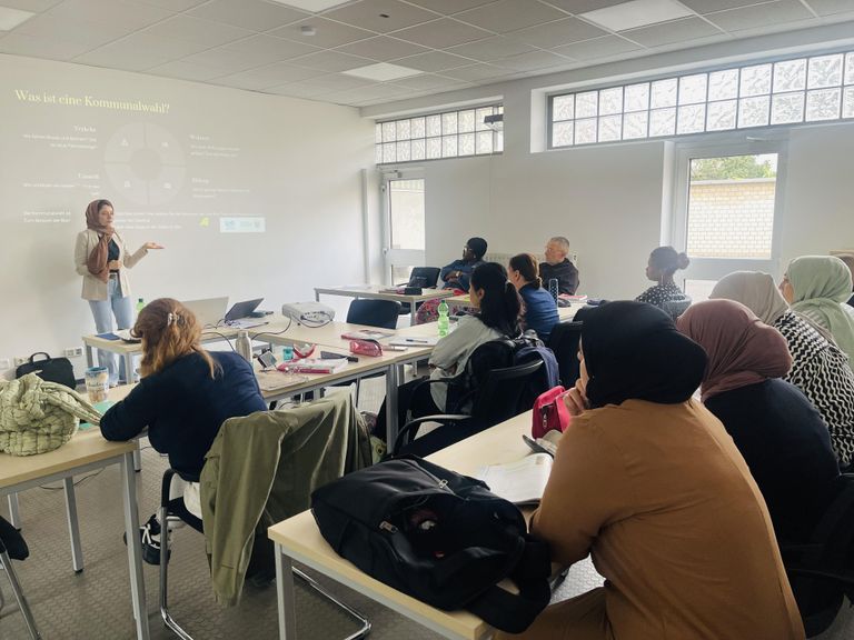 Menschen in einem Seminarraum hören einen Vortrag.