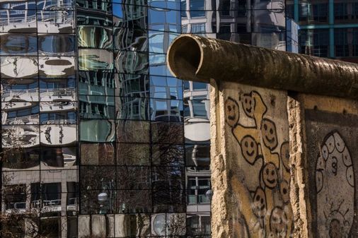 Ein Rest der Berliner Mauer, im Hintergrund ein modernes Bürogebäude